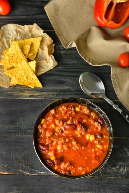 Koyu ahşap arka planda lezzetli kırmızı biberli kase.