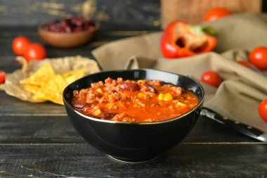 Koyu ahşap arka planda lezzetli kırmızı biberli kase.