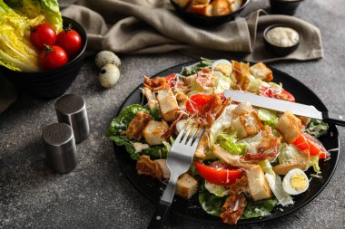 Lezzetli Sezar salatası ve arkaplandaki malzemelerle dolu bir tabak.