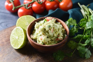 Lezzetli guacamole, domates ve limon renkli ahşap arka planda, yakın plan