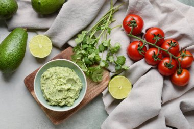 Lezzetli guacamole, domates, avokado ve açık arkaplanda limon ile kase