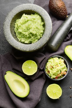 Lezzetli guacamole, avokado ve koyu arkaplanda limon ile havan topu