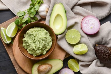 Lezzetli guacamole, avokado ve koyu ahşap arka planda limon ile kase