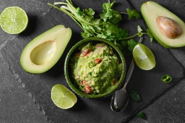 Lezzetli guacamole, avokado ve koyu arkaplanda limon.