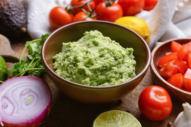 Ahşap arka planda lezzetli guacamole ile kase, yakın plan