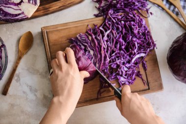 Masada taze mor lahana kesen bir kadın.