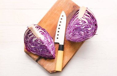 Açık ahşap arka planda taze mor lahana parçaları olan tahta.