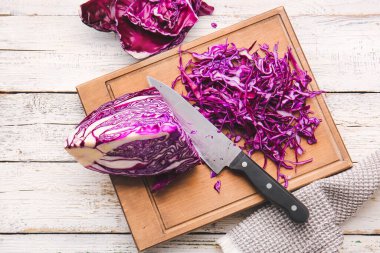 Açık ahşap arka planda kesilmiş taze mor lahanalı tahta.