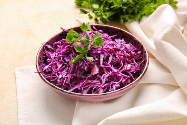 Açık arkaplanda taze mor lahana ve maydanozlu kase.