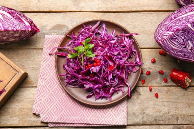 Kesilmiş taze mor lahana ve ahşap zemin üzerinde nar tabağı.