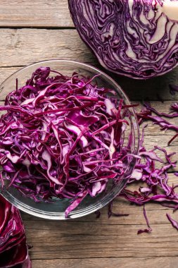 Bowl with cut fresh purple cabbage on wooden background