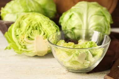 Bowl with fresh chopped cabbage on light wooden table