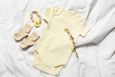 Baby clothes and teether on bed