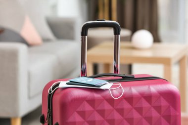 Packed suitcase with immune passport and medical masks in room