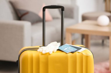 Packed suitcase with immune passport, medical mask and rubber gloves in room