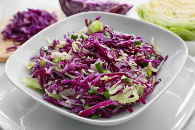 Plate with tasty cabbage salad on table