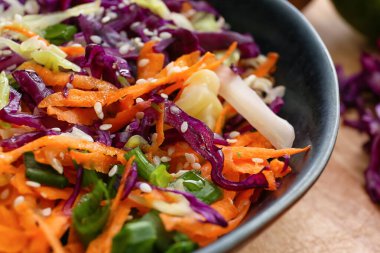 Bowl with tasty cabbage salad on wooden table, closeup