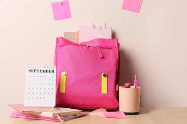 Okul çantası ve kırtasiye malzemeleri masanın üstünde.