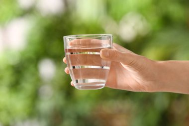 Açık havada bir bardak taze soğuk suyla kadın eli, yakın plan.