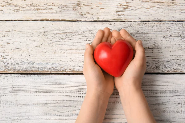 Mani Bambino Con Cuore Rosso Sfondo Legno Chiaro — Foto Stock