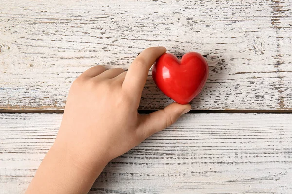 Mano Del Bambino Con Cuore Rosso Sfondo Legno Chiaro — Foto Stock