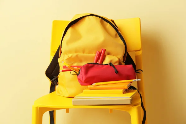 背景色背景下椅子上的学校背包和文具 — 图库照片