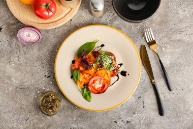 Plates with tasty tomato carpaccio and ingredients on grunge background