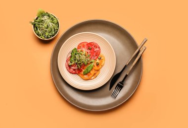 Plate with tasty tomato carpaccio and fresh sprouts on color background