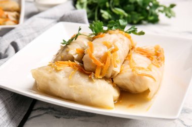 Hafif arka planda içi doldurulmuş lahana dürümlü tabak.