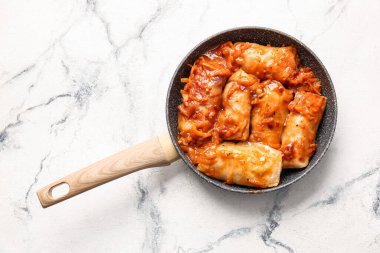 Hafif arka planda lezzetli lahana dürümlü kızartma tavası.