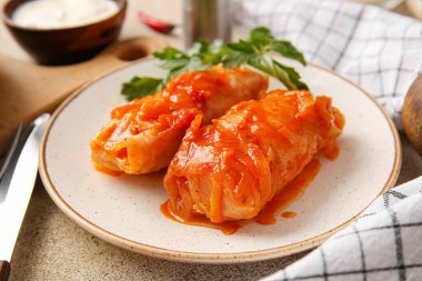 Hafif arka planda içi doldurulmuş lahana dürümlü tabak.