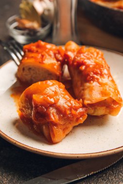 Koyu arkaplanda lezzetli lahana ruloları olan tabak.