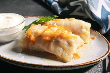 Koyu arkaplanda lezzetli lahana ruloları olan tabak.