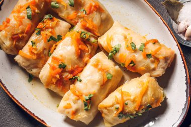 Gri arka planda lezzetli lahana sarmaları olan tabak.