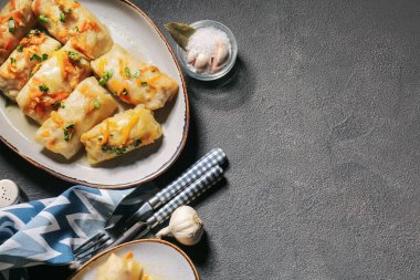 Koyu arkaplanda lezzetli lahana ruloları olan tabak.