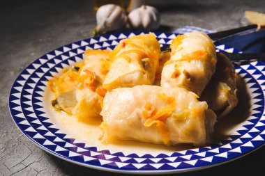 Gri arka planda lezzetli lahana sarmaları olan tabak.