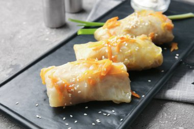 Gri arka planda lezzetli lahana dürümlü tabak, yakın plan.