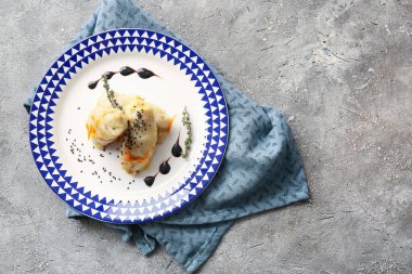 Gri arka planda lezzetli lahana sarmaları olan tabak.