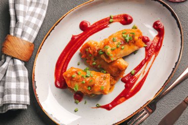 Koyu arkaplanda lezzetli lahana ruloları olan tabak.