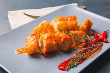 Koyu arkaplanda lezzetli lahana ruloları olan tabak.