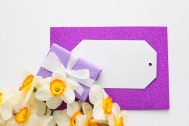 Güzel nergisler, hediye kutusu ve beyaz arka planda boş bir kart.