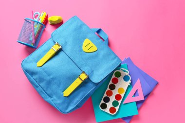 Renk arkaplanında kırtasiye malzemesi olan okul çantası