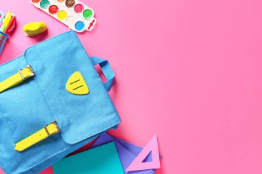 Renk arkaplanında kırtasiye malzemesi olan okul çantası