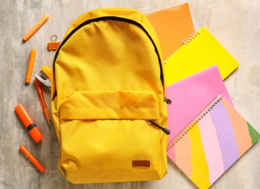 Açık arkaplanda kırtasiye malzemesi olan okul çantası