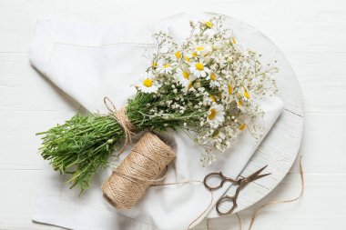 Bir buket güzel papatya çiçeği, makas ve ip açık ahşap arka planda