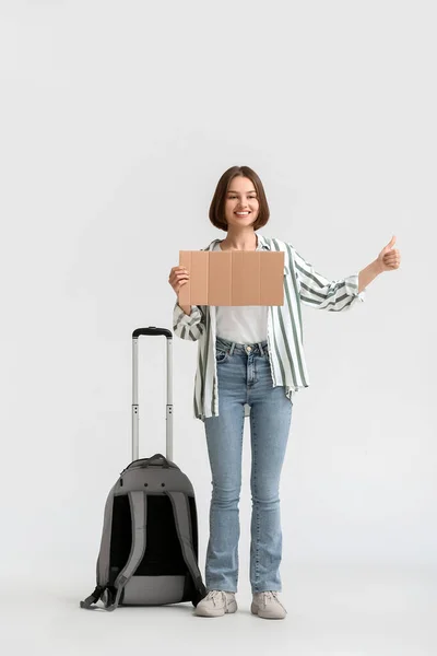 Junge Frau Mit Pappe Und Koffer Trampt Auf Hellem Hintergrund — Stockfoto