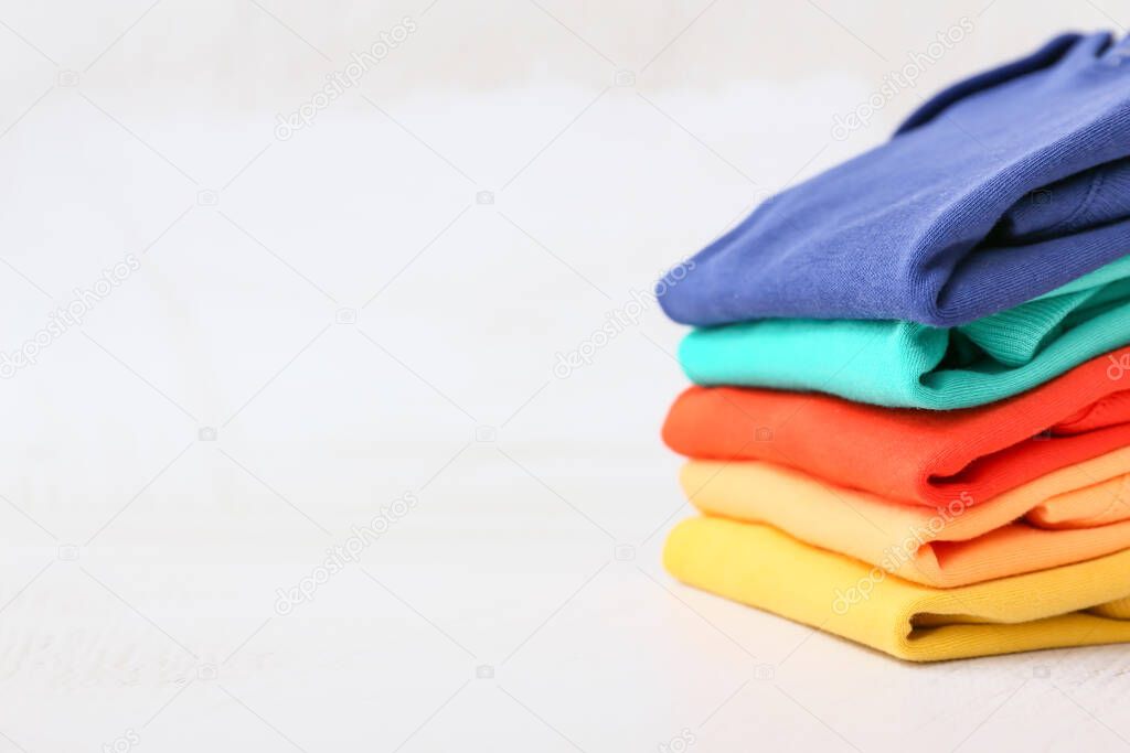 Stack of baby clothes on light background