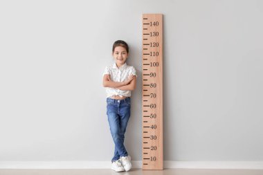 Işık duvarının yanında boyunu ölçen küçük kız.