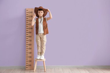 Little boy measuring height near color wall clipart