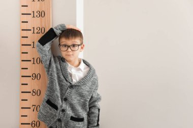 Evde boyunu ölçen küçük bir çocuk.